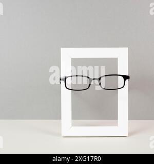 Home interior poster mock up with wooden frame and eyeglasses, gray wall background, copy space for text and pictures Stock Photo