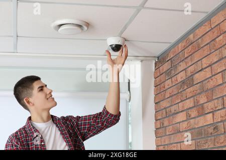 Technician installing CCTV camera on ceiling indoors Stock Photo