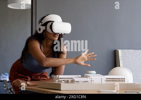 Using VR headset, woman interacting with architectural model in office, copy space Stock Photo
