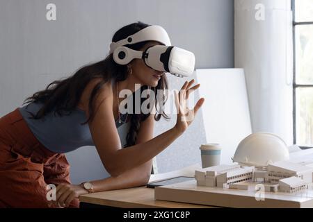 Using VR headset, woman interacting with architectural model in office, copy space Stock Photo