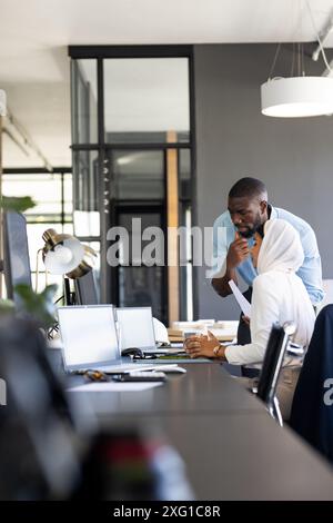 Discussing project details, colleagues collaborating at office desk with laptops, copy space Stock Photo
