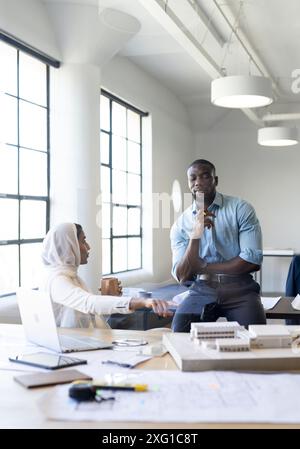 Discussing project, business colleagues collaborating with laptop and architectural model in office Stock Photo
