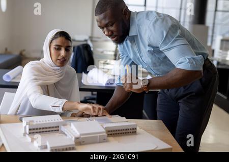 Architects discussing building model, collaborating on project in modern office Stock Photo