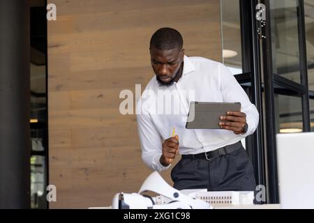 Using tablet and pencil, businessman analyzing architectural model in office Stock Photo