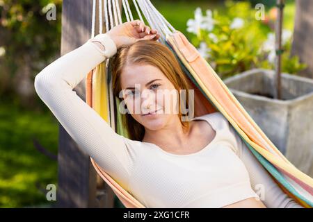 Relaxing in hammock, woman enjoying leisure time outdoors in garden Stock Photo