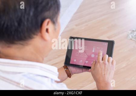 Using tablet, senior senior man controlling smart home system with weather app Stock Photo