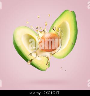 avocado with oil splash on a light pink background. Stock Photo