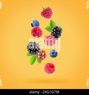 falling raspberries, blackberries and blueberries on a yellow background. Stock Photo