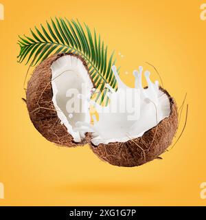 coconuts with milk splash and leaf on a yellow background. Stock Photo