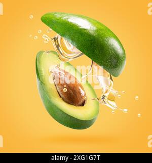 avocado with oil splash on a light green background. Stock Photo