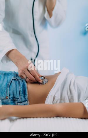 Pediatrician gastroenterologist doing abdominal examination with stethoscope. Stock Photo