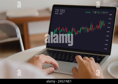 Person analyzing stock market data on laptop with candlestick chart, financial trading. Stock Photo