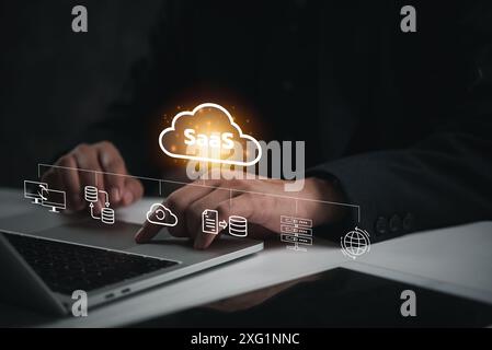 Hand interacting with SaaS icons above laptop, showcasing software as a service concept. Perfect for technology, cloud computing, digital business sol Stock Photo