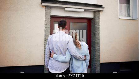 Newlyweds embracing outside their first home, planning a future together in real estate as homeowners and potentially as realtors. Stock Photo