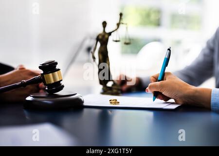 Young couple, one Caucasian and one Hispanic, consulting with a lawyer in court to sign a divorce agreement document. Stock Photo