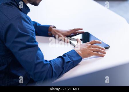 Using tablet and smartphone, businessman working at desk in office, copy space Stock Photo
