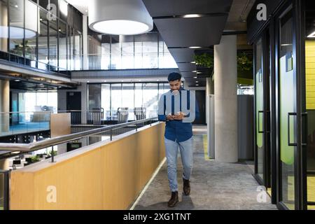 Walking in modern office, man using smartphone and focusing on work Stock Photo