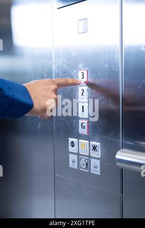 Pressing elevator button, person selecting third floor in modern office building Stock Photo