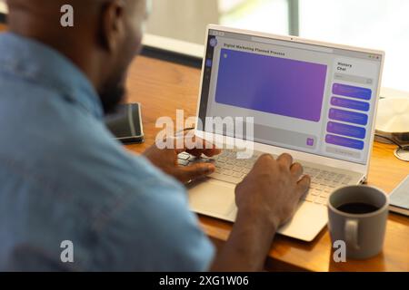 Using AI chatbot on laptop, man working on digital marketing project at home office desk Stock Photo