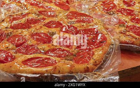 Neapolitan pizza with cheese and red tomatoes vacuum packed with an airtight bag on sale at the Italian market stall Stock Photo