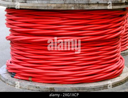 large reel of high voltage insulated red electrical cable in power company warehouse Stock Photo