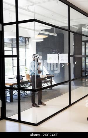 Using VR headset, businessman exploring virtual environment in modern office, copy space Stock Photo