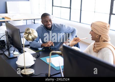 Collaborating at work, colleagues discussing project at office desk with computers Stock Photo