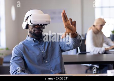 Using VR headset, man interacting with virtual interface in modern office Stock Photo