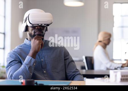 Using VR headset, businessman sitting at desk in modern office environment Stock Photo