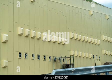 A large building with many windows and vents. The building is yellow and has a lot of windows. Stock Photo