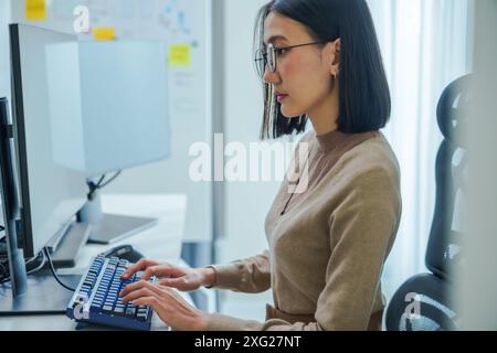 Asian prompt engineer develop coding app with software data sitting in front of computer monitor at office Stock Photo