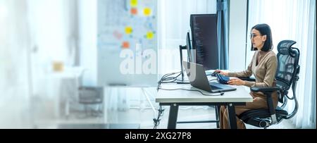 Asian prompt engineer develop coding app with software data sitting in front of computer monitor at office Stock Photo
