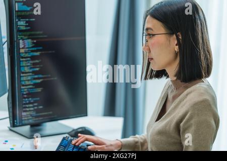 Asian prompt engineer develop coding app with software data sitting in front of computer monitor at office Stock Photo