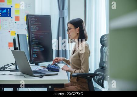 Asian prompt engineer develop coding app with software data sitting in front of computer monitor at office Stock Photo