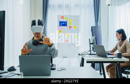 Asian and Indian developer program coding sent to virtual reality headset to implement ai project at office Stock Photo
