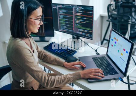 Asian prompt engineer develop coding app with software data sitting in front of computer monitor at office Stock Photo