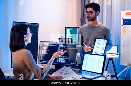 asian and Indian Developer team discussion feedback analysis coding data with software computer at office Stock Photo