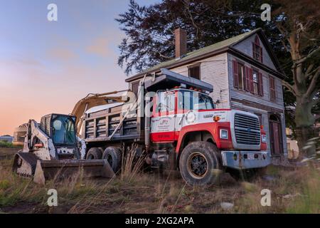 Plymouth, Massachusetts, USA - Excavation equipment lines up next to an old house in Massachusetts as contractors prepare for demolition. Stock Photo