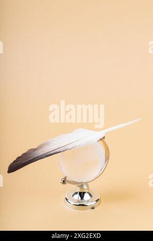 Glass Globe with Balancing Bird Feather, Fragile Balance of Earth's Ecosystem Concept, Copy Space Stock Photo