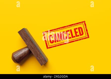 Cancellation message. Wooden stamp imprints the word canceled on a yellow background, symbolizing change in business or travel. 3d render. Stock Photo