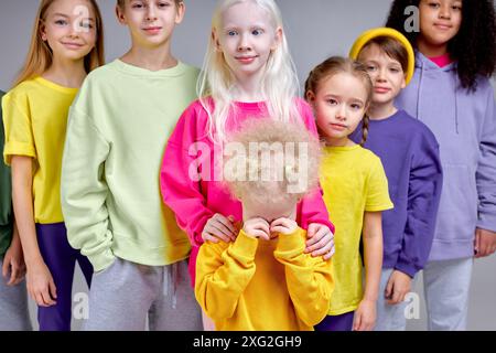 upset unhappy little girl crying wiping her eyes, her multiethnic friends standing behind her support , protect her, isolated white background protest of bullying friendship Stock Photo