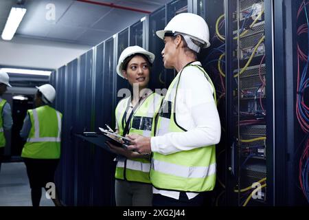 Data center, women and tablet with clipboard, safety and programmer in computer engineering. Female people, inspection and tech for hardware, security Stock Photo