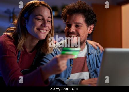 Caucasian couple doing online shopping from home using a laptop and a credit card. Stock Photo
