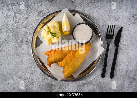 Deep fried coated fish fillet with potato salad on stone table Stock Photo
