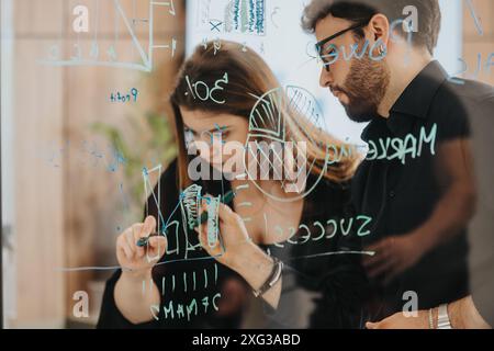 Business team collaboratively brainstorming with sticky notes on glass wall Stock Photo