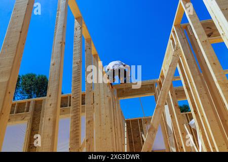 Using an air hammer contractor nails wooden beams to frame of housing ...