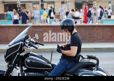 Man on motorbike stopped and using smartphone on city street Stock Photo