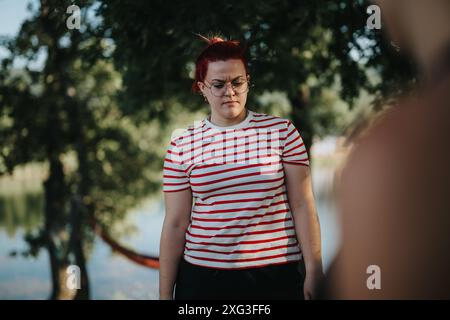 Young woman with striped shirt enjoying a peaceful moment in nature by a lake Stock Photo