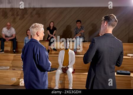 Rear View On Two caucasian managers speaker in lecture hall talking to audience students, in conference hall, group of multi-ethnic people in the back Stock Photo