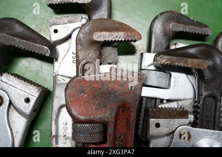 Old rusty pipe wrench and other tools on green background, close up Stock Photo